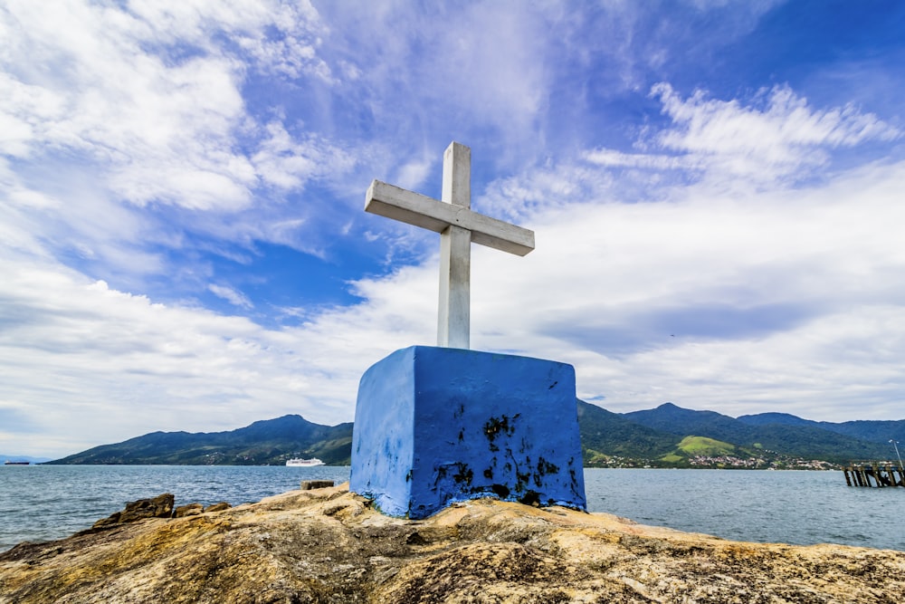 blue cross on brown rock under blue sky during daytime