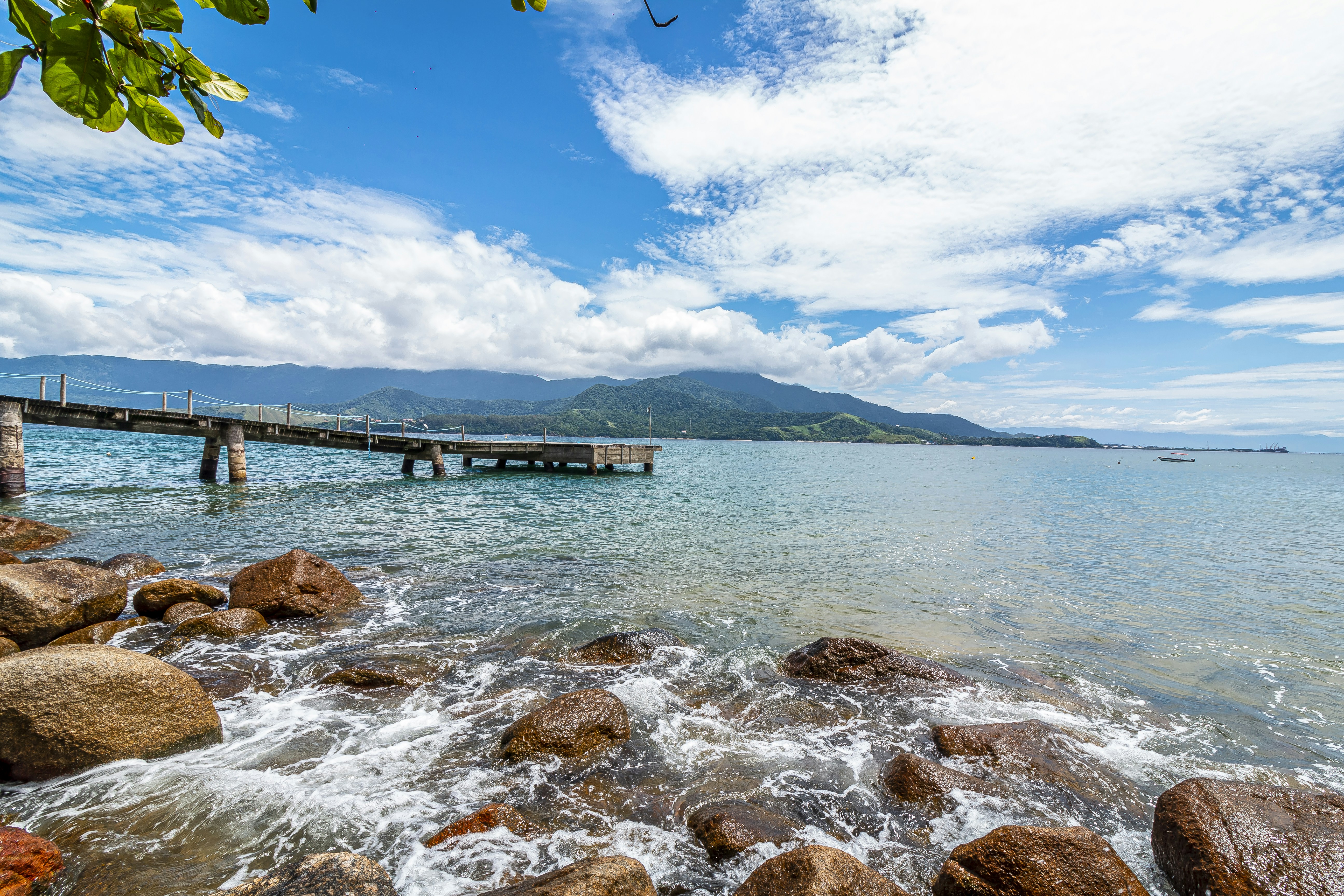 A wooden jetty over crystal clear water at an Ilhabela Beach