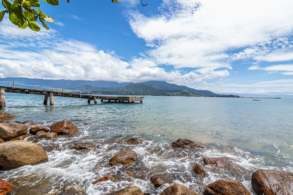 brown wooden dock on sea under blue sky during daytime