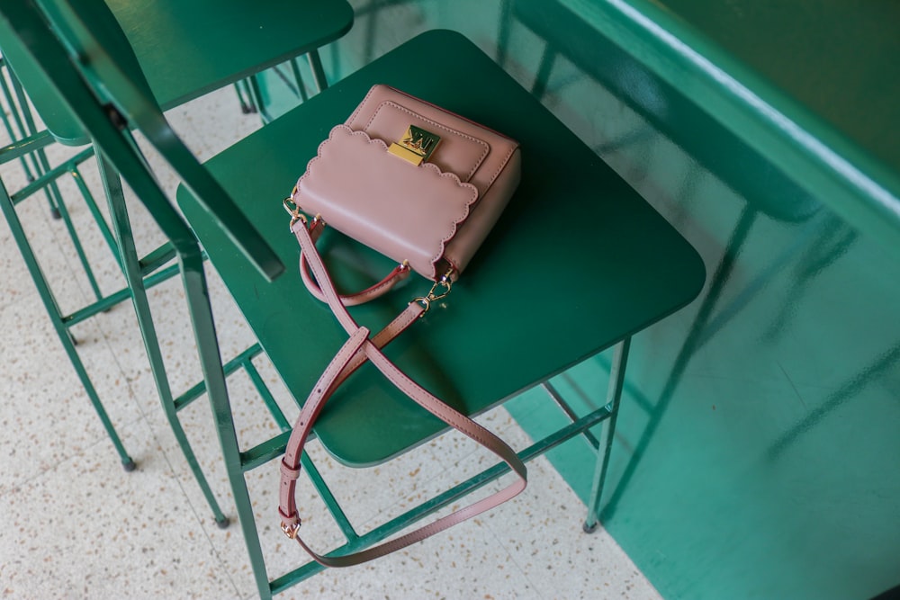 brown leather sling bag on green chair