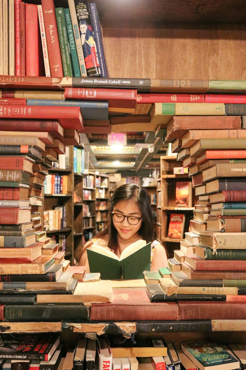 Frau im grünen Hemd sitzt auf Büchern