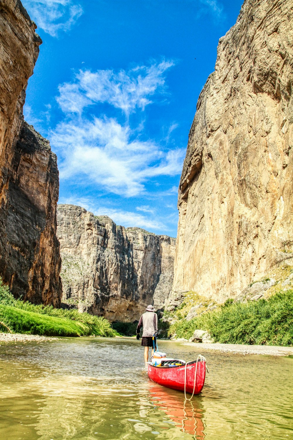 woman in white shirt and black skirt standing on pathway between brown rock formation during daytime