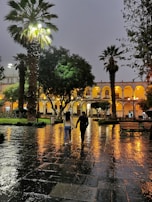 A couple walking hand-in-hand along Dubai's sparkling Marina at night.