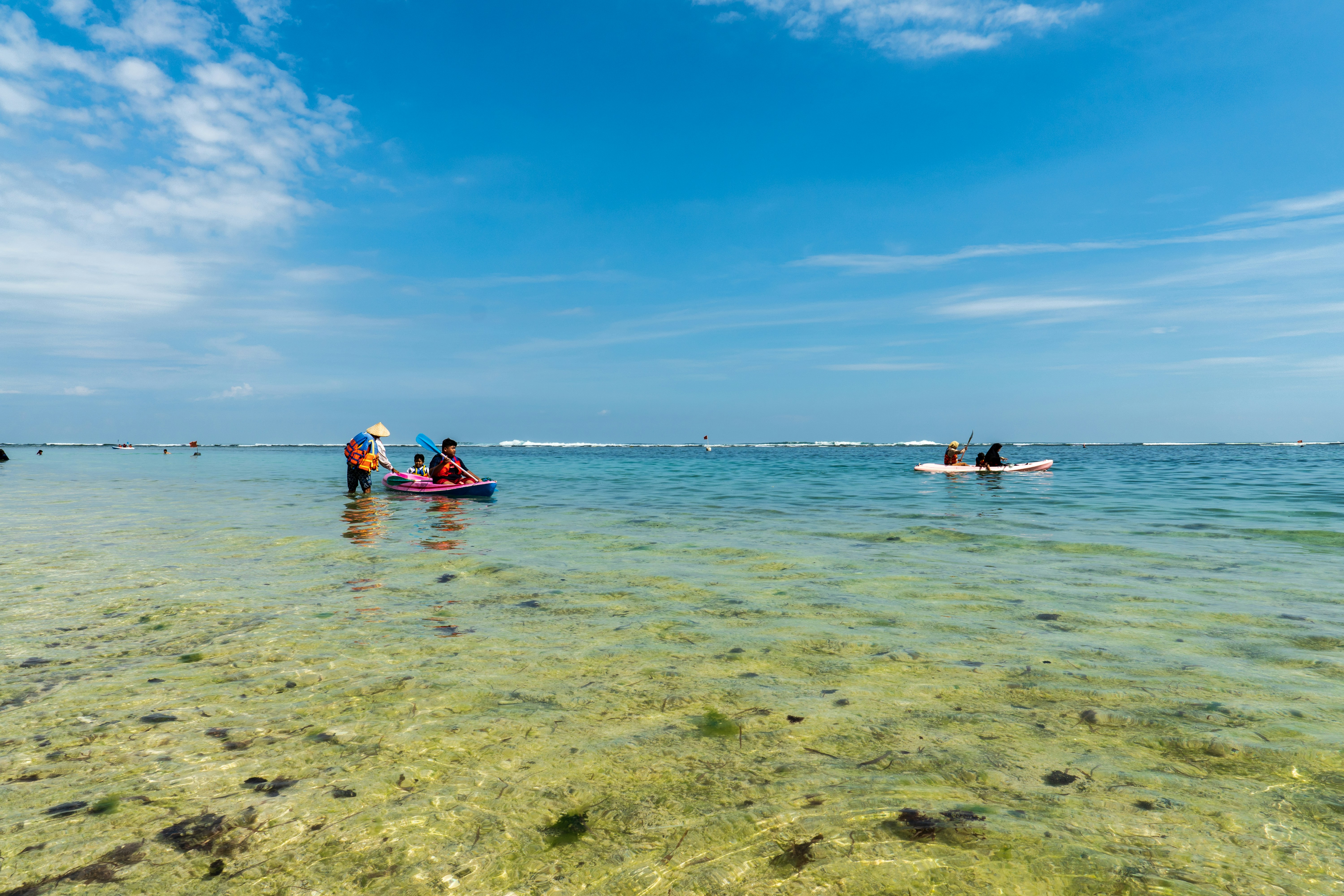 Kayak rouge sur une mer bleue cristalline sous un ciel ensoleillé à Bali.