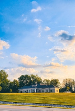 A modern single-family home with large windows and a landscaped front yard under a clear sky.