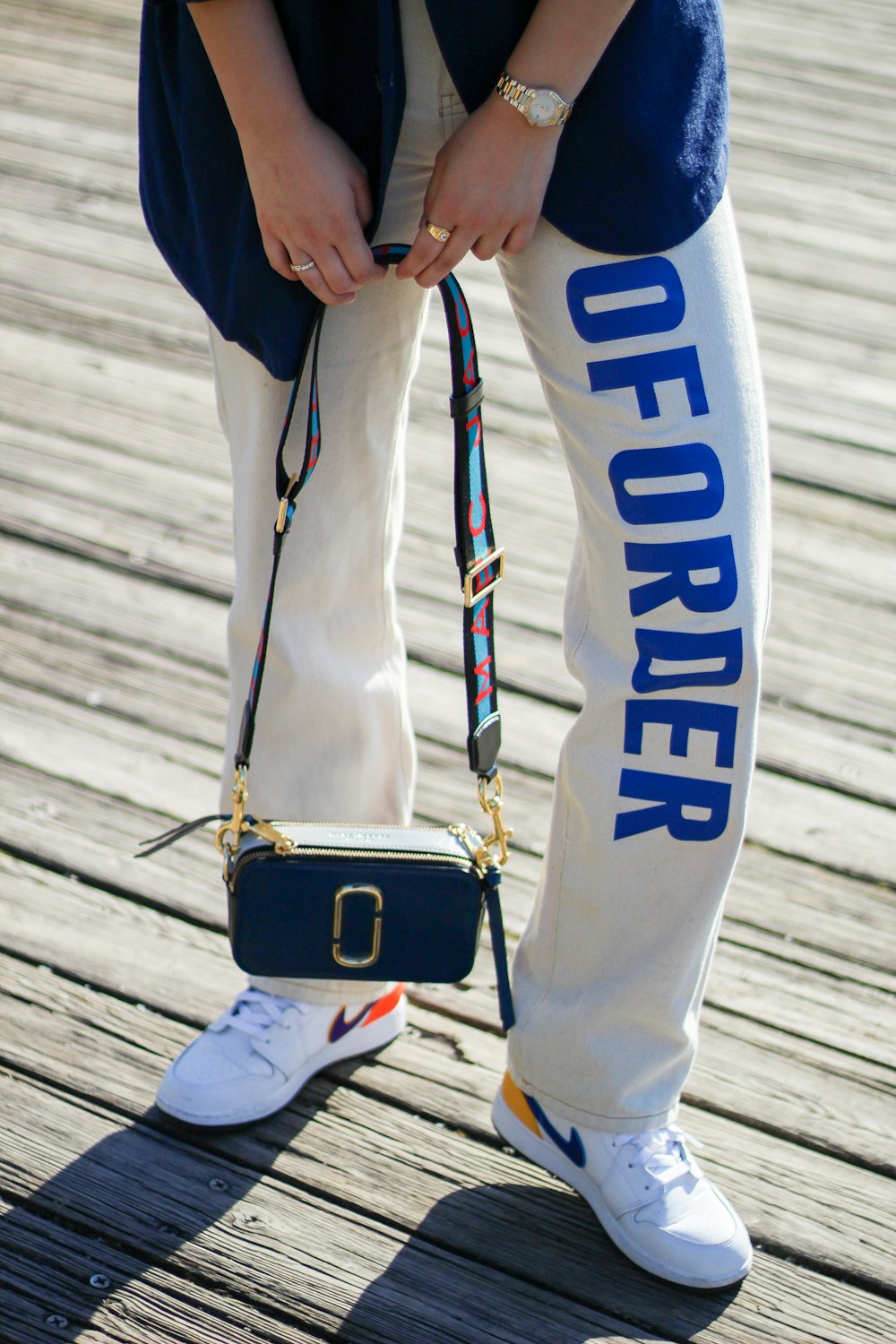 person in black jacket and white pants with brown leather sling bag