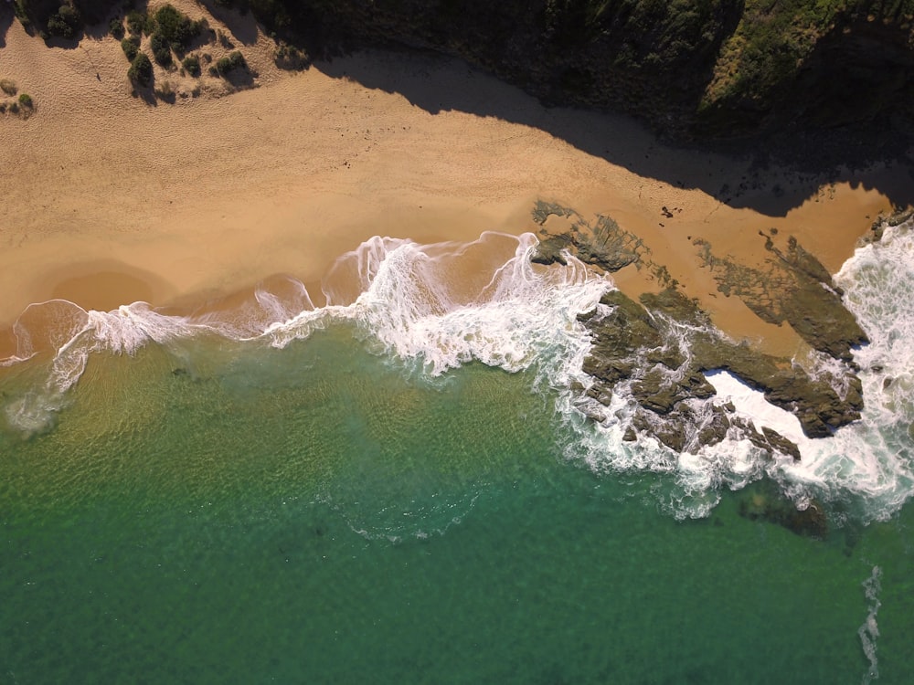 aerial view of ocean waves crashing on shore during daytime