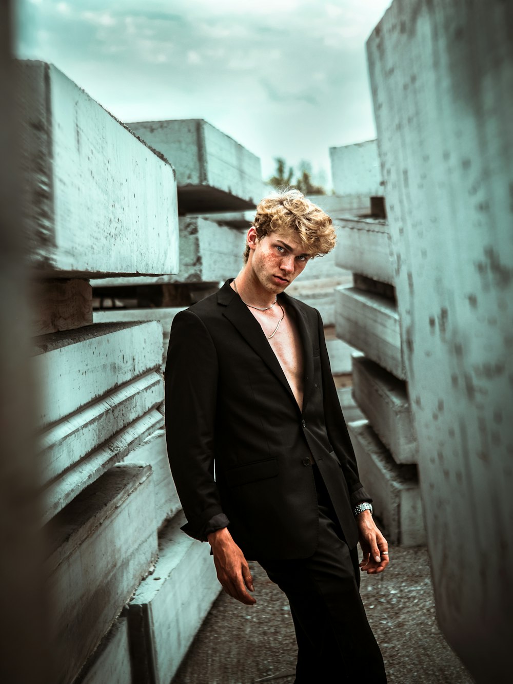 man in black blazer standing beside gray wall