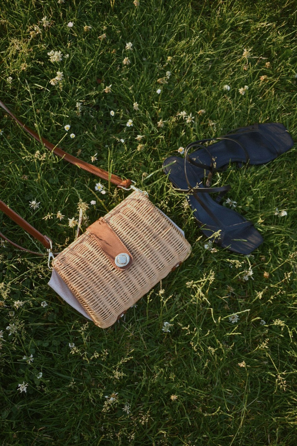 緑の芝生に茶色の革のスリングバッグ