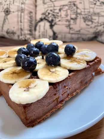 A beautifully plated protein waffle with banana slices and a drizzle of honey on a ceramic plate.