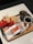 A fast food meal consisting of two packs of French fries, a wrapped burger, a glass of soda with ice, and a cup of black coffee on a tray with branded packaging.