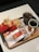 A fast food meal consisting of two packs of French fries, a wrapped burger, a glass of soda with ice, and a cup of black coffee on a tray with branded packaging.