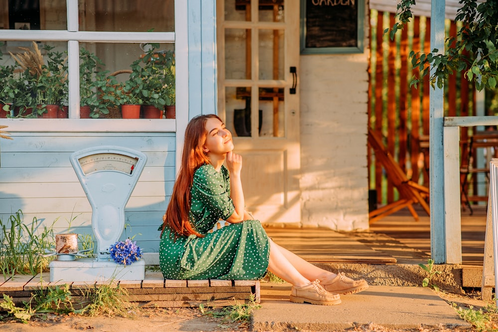 woman in green dress sitting on brown concrete floor