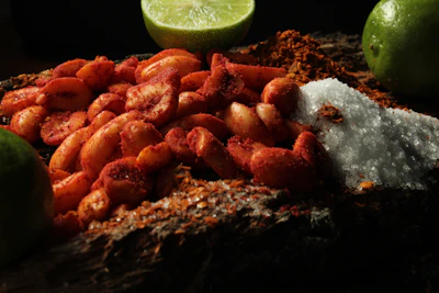 A bowl of roasted peanuts with a light sprinkle of chili powder and lime wedges on the side