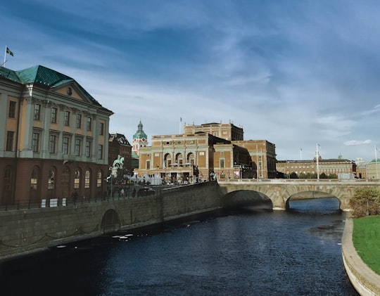 brown concrete building near river under blue sky during daytime in Royal Swedish Opera Sweden