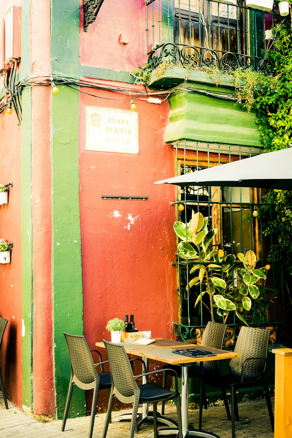 brown wooden table and chairs near red concrete building