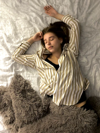 woman in white and black striped long sleeve shirt lying on bed