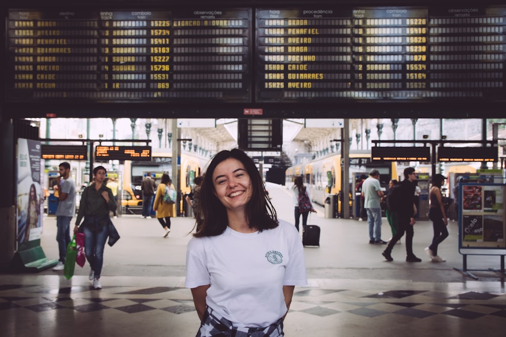 Femme en T-shirt à col rond blanc debout sur des carreaux de sol blancs