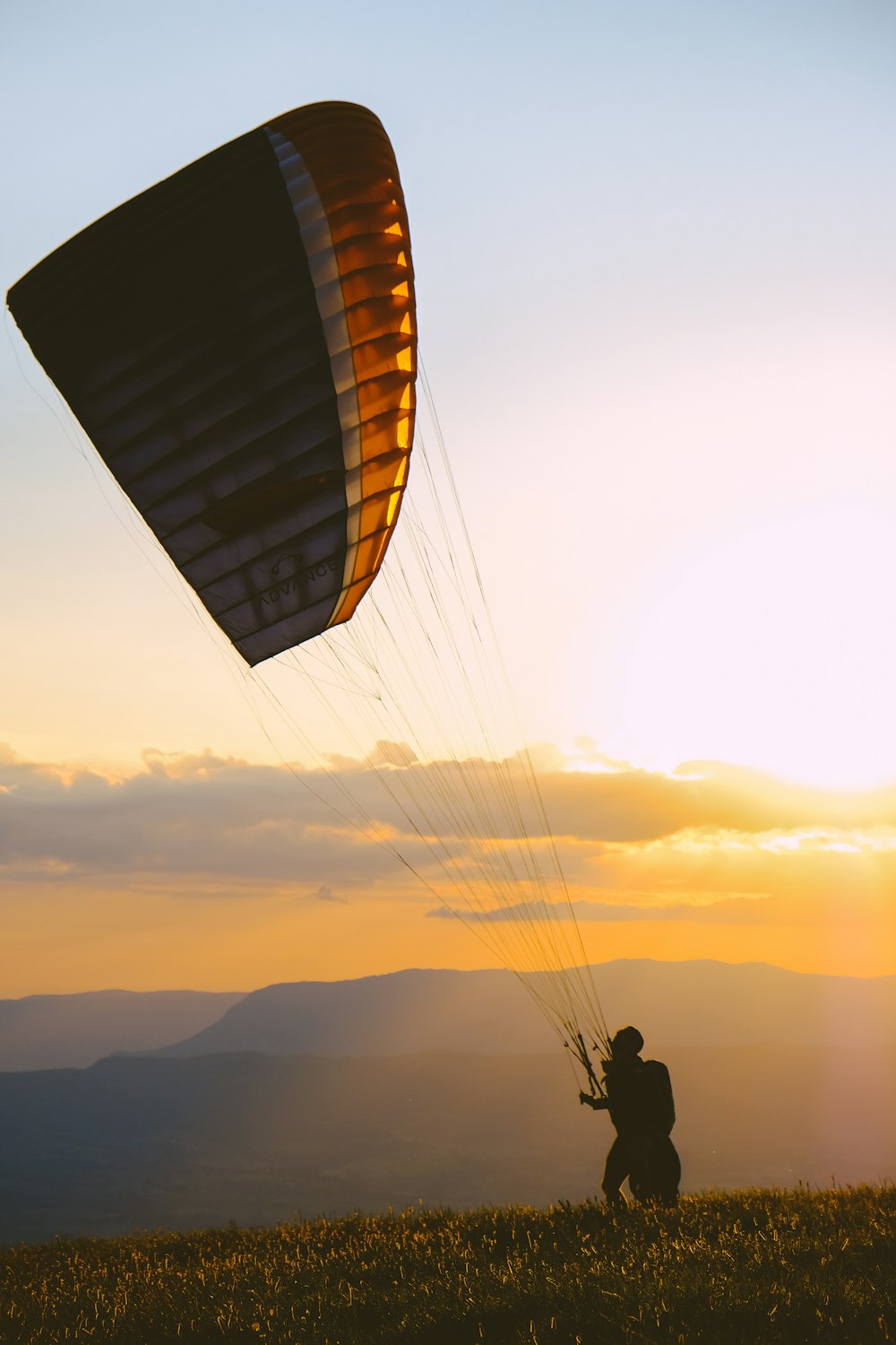 Silhouette der Person am Fallschirm während des Sonnenuntergangs