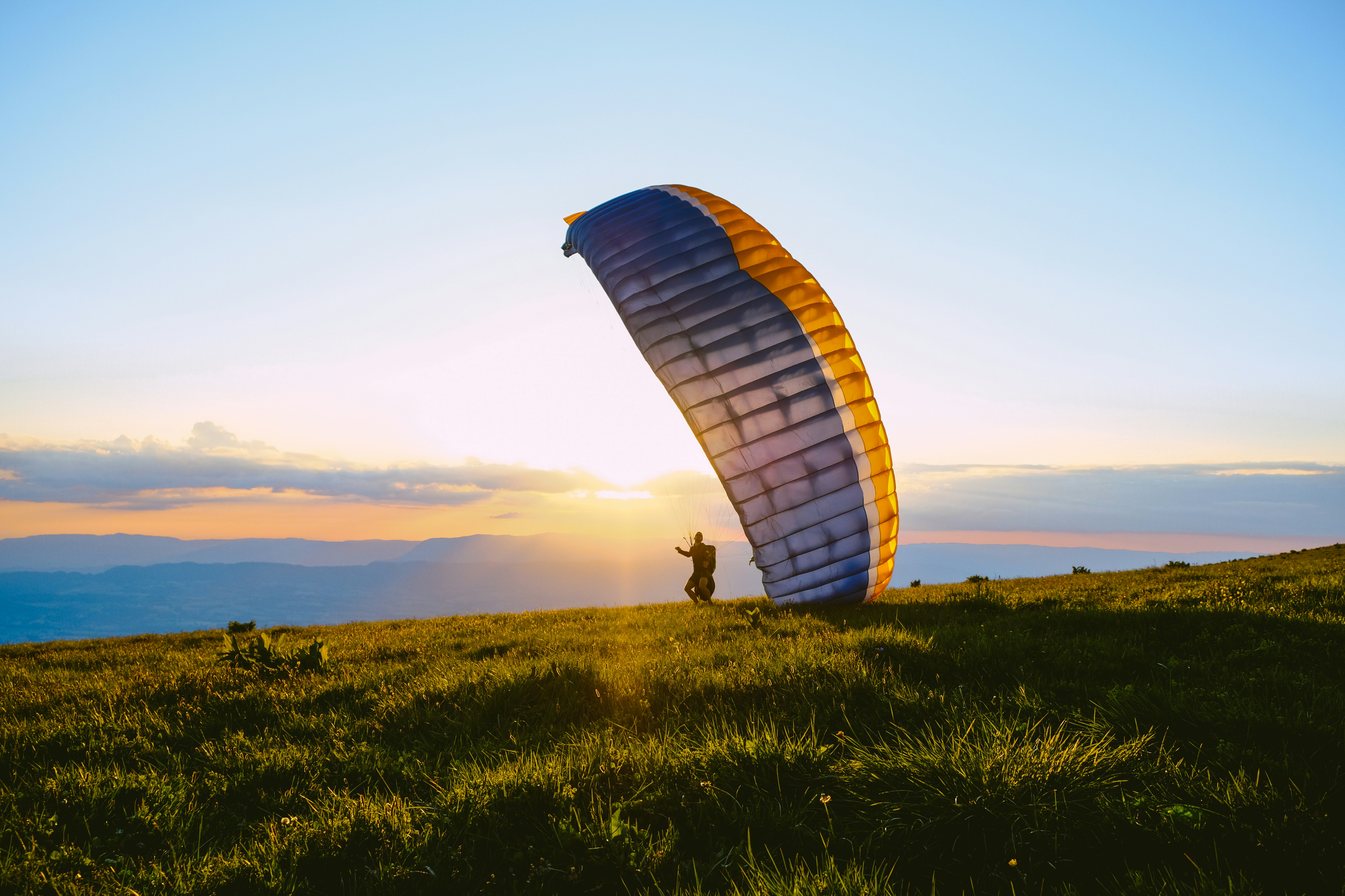silhouette of person riding parachute during sunset