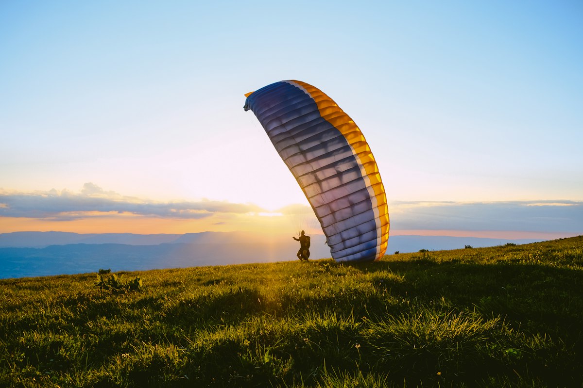 Paragliding silhouette over mountains at sunset
