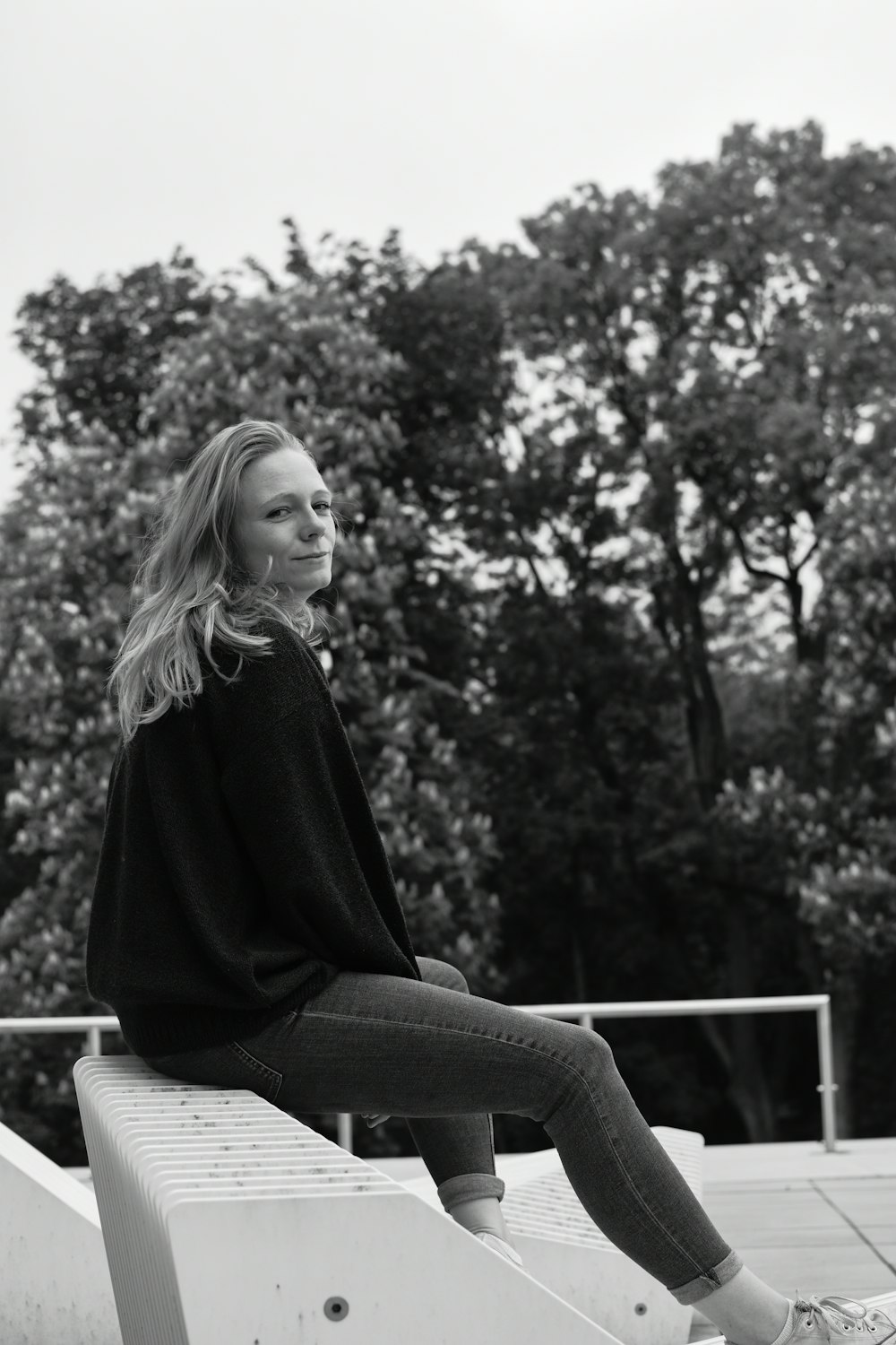 woman in black long sleeve shirt and black denim jeans sitting on bench