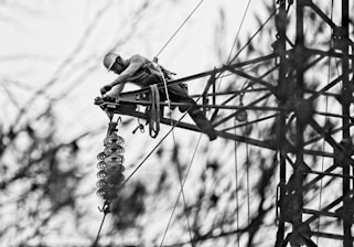 Technician performing welding repair on a tall steel structure using climbing gear.