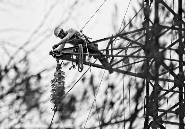 Technician carefully installing fiber optic cables on a tower with safety gear.
