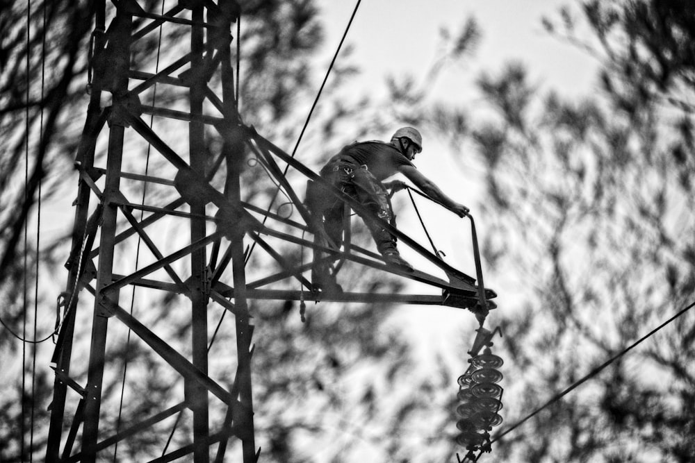 grayscale photo of man climbing on metal ladder