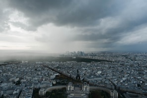 A panoramic view of a Colombian city skyline under a cloudy sky, highlighting contrasts.