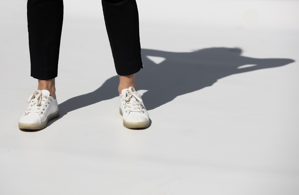 Person in schwarzen Hosen und weißen und braunen Nike-Sneakers