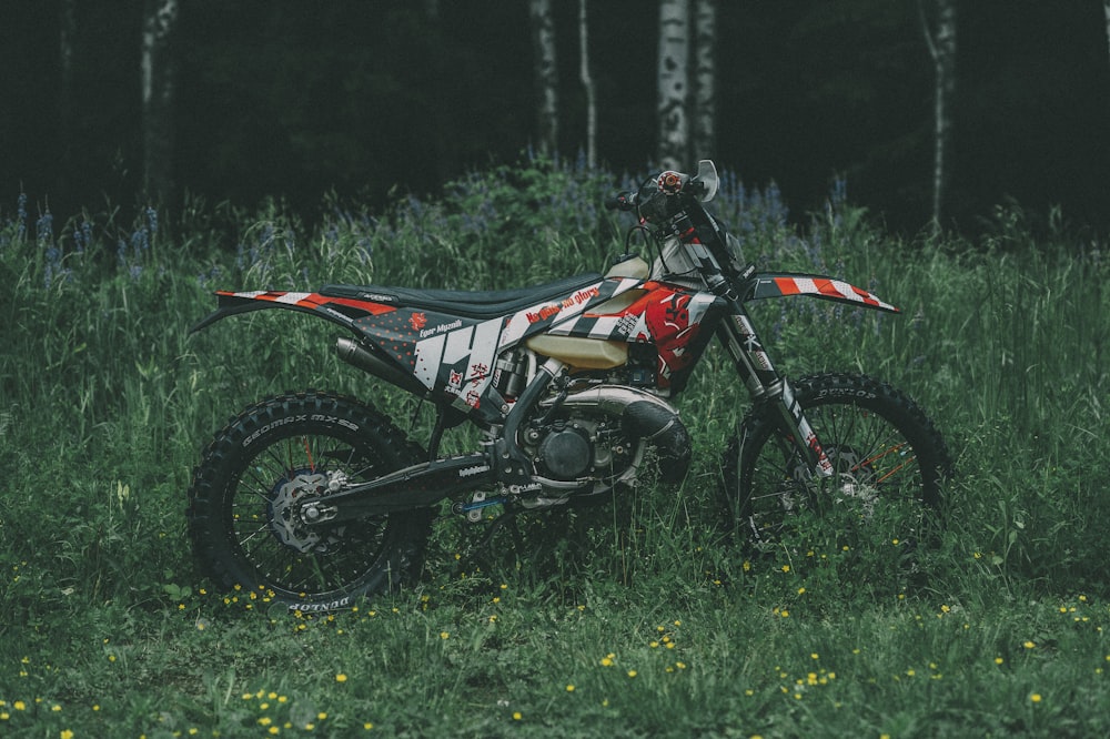 red and black motocross dirt bike on green grass field during daytime