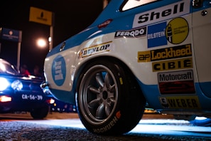 Close-up of the race car adorned with vibrant sponsor logos under bright track lights.