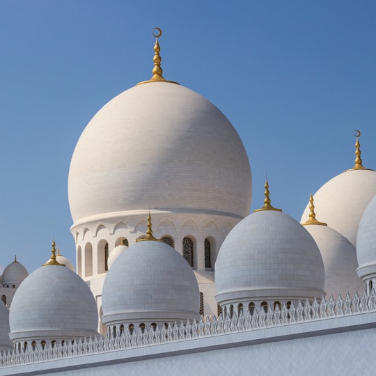 white and gold dome building under blue sky during daytime in Sheikh Zayed Grand Mosque Center United Arab Emirates