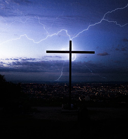 silhouette of cross under cloudy sky during night time