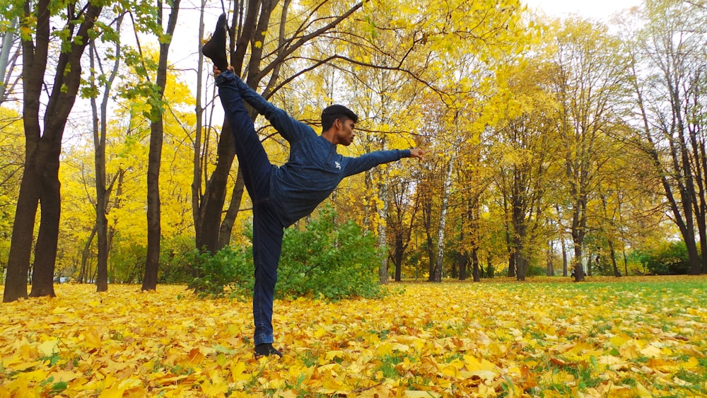 man in black long sleeve shirt and black pants standing on yellow leaves on ground during