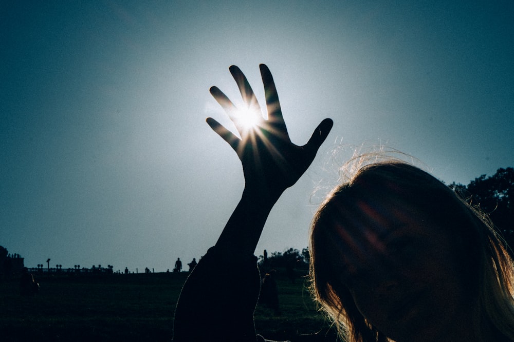 silhouette of woman raising her hand