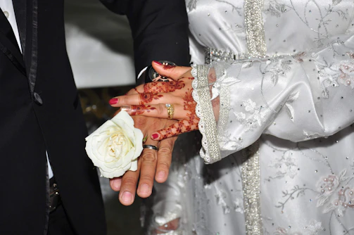 Close-up of hands adorned with henna and wedding rings, symbolizing commitment and faith.
