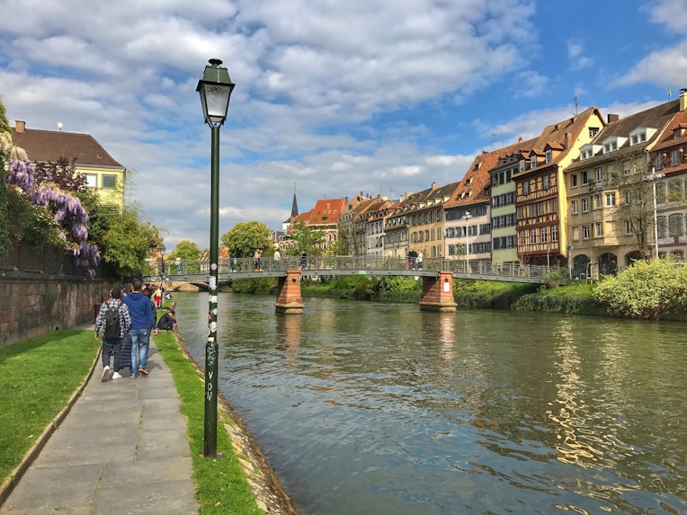 people walking on sidewalk near body of water during daytime