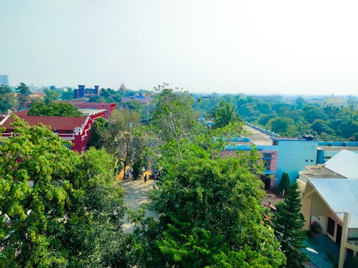 A vibrant aerial view of Transvers Village showcasing its blend of permaculture gardens and bioarchitectural homes under a clear sky.