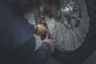 person in black jacket holding bicycle wheel