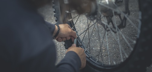 person in black jacket holding bicycle wheel