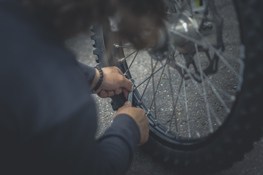 person in black jacket holding bicycle wheel