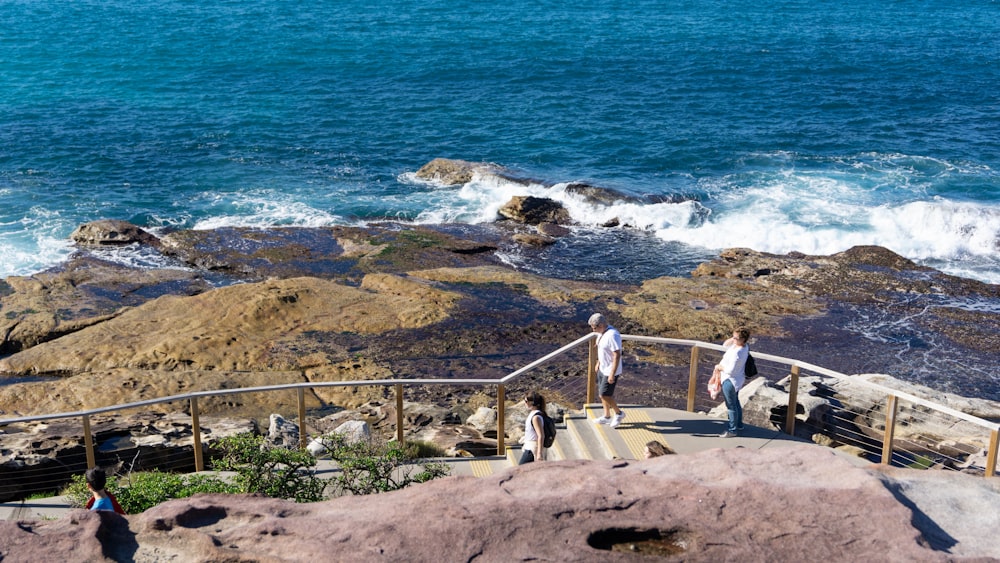 people walking on brown concrete stairs near body of water during daytime