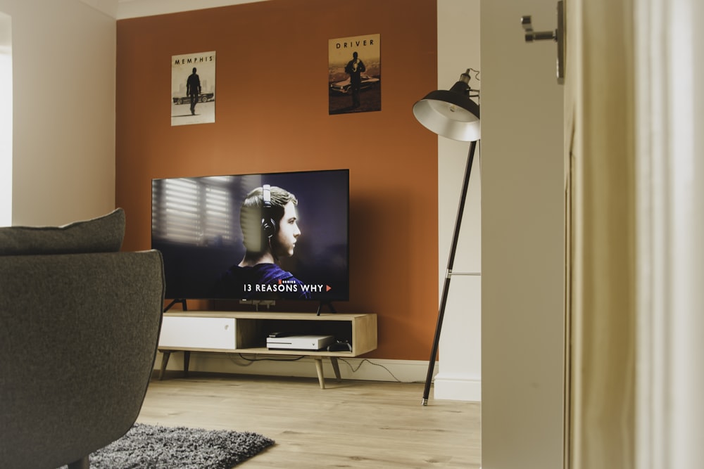 TV nera a schermo piatto accesa vicino a Torchiere bianca e nera
