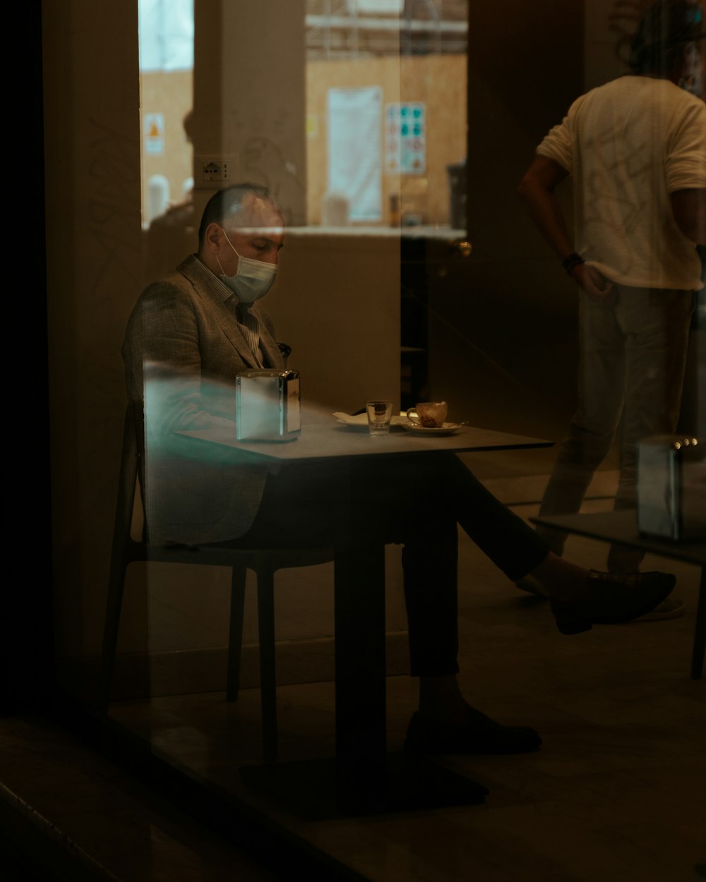 woman in white long sleeve shirt and black pants standing beside table