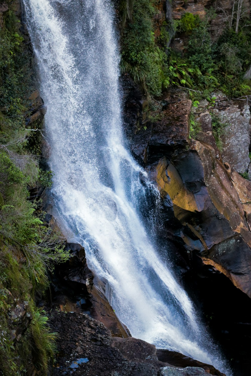 water falls on brown rocky mountain