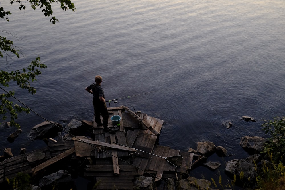 man in black shirt standing on brown wooden boat on body of water during daytime