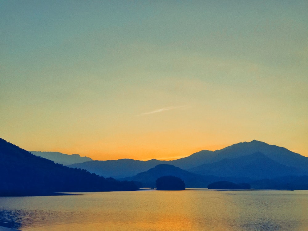 body of water near mountain during daytime