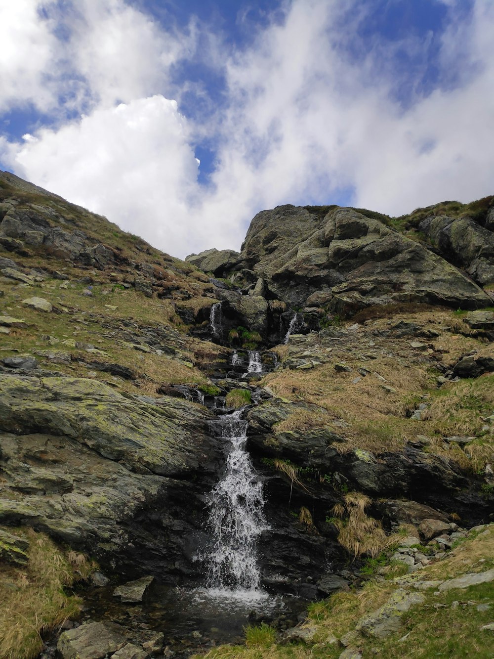 cachoeiras na montanha rochosa sob o céu azul durante o dia